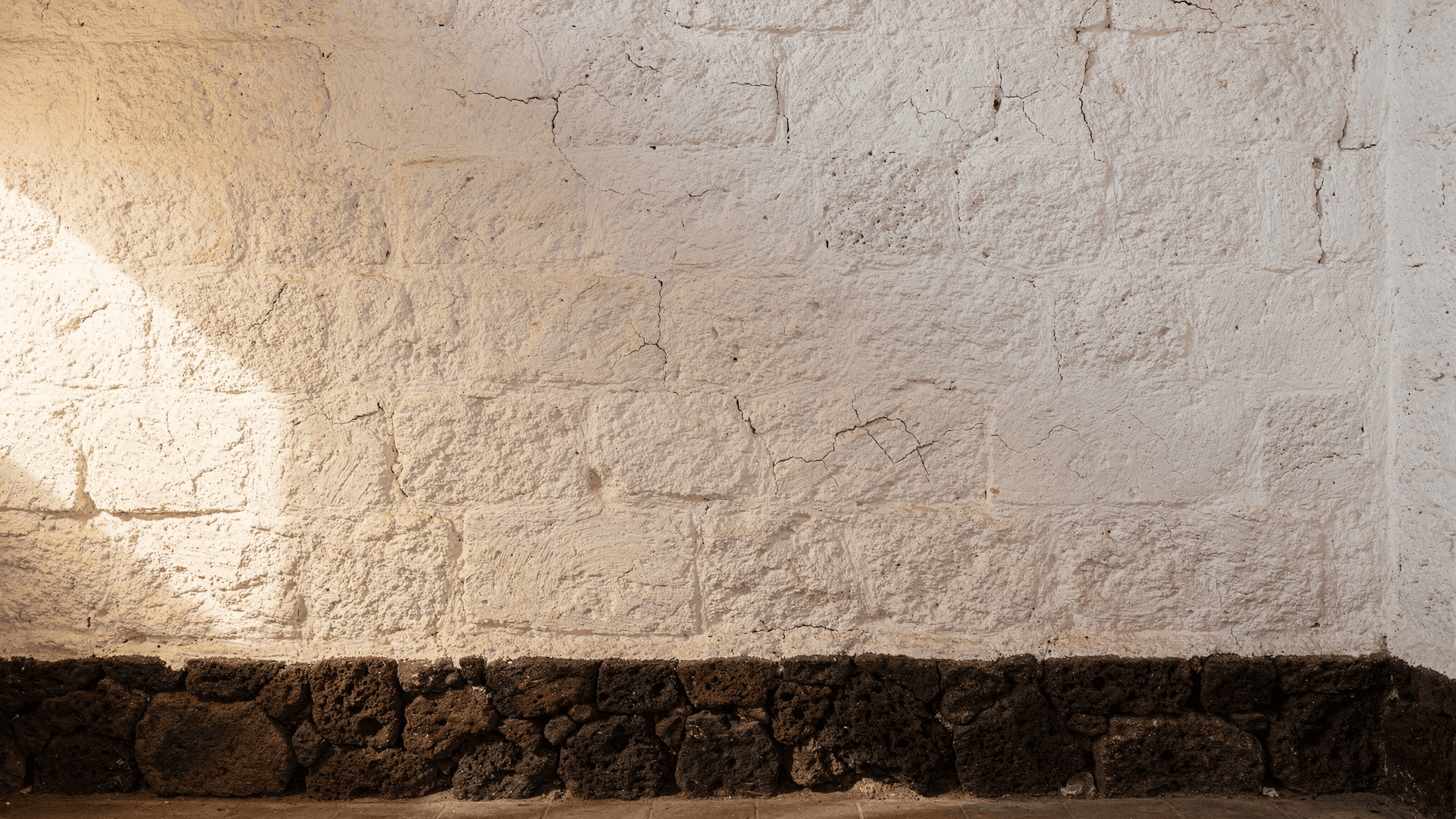 Pared encalada de una casa canaria con zócalo de piedra volcánica